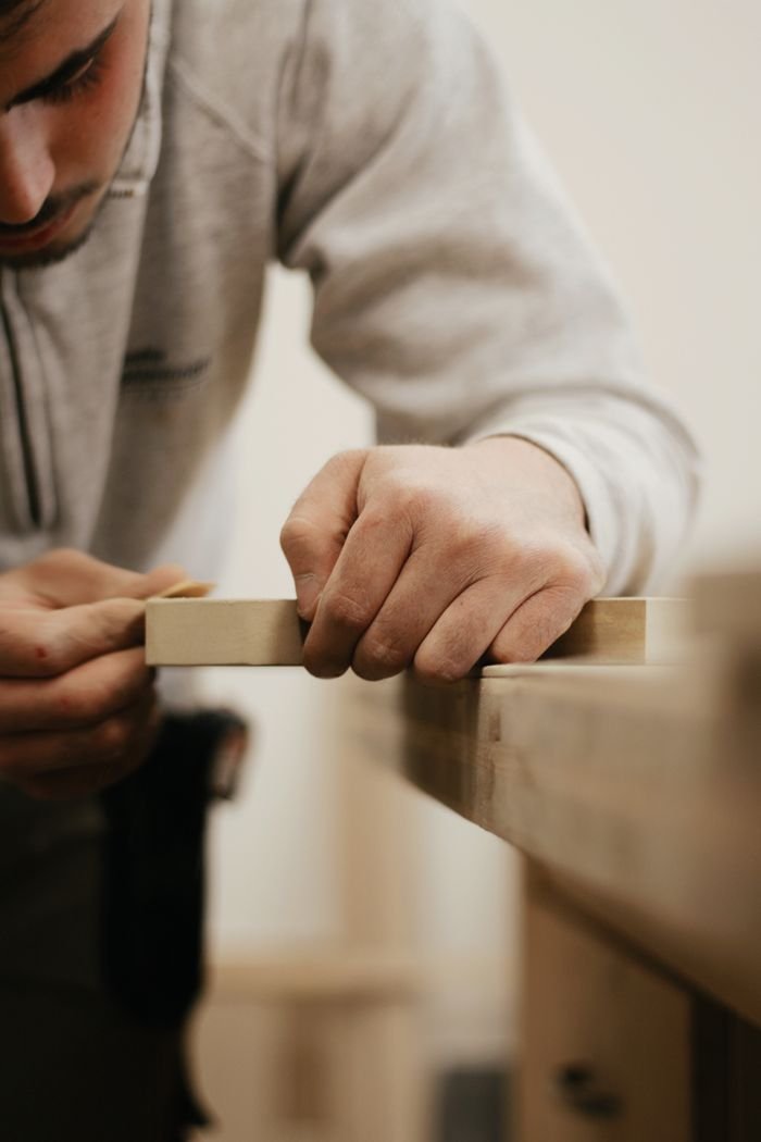 Mastering the First Impression: Your intriguing post title goes here Close-up of a man meticulously sanding wood, showcasing craftsmanship.