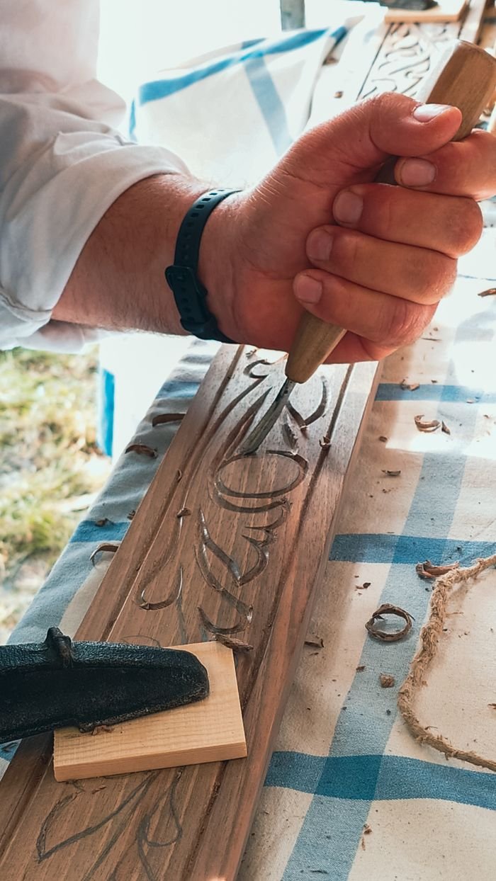 Detailed view of a craftsman hand carving intricate patterns into wood at Budapest art fair.