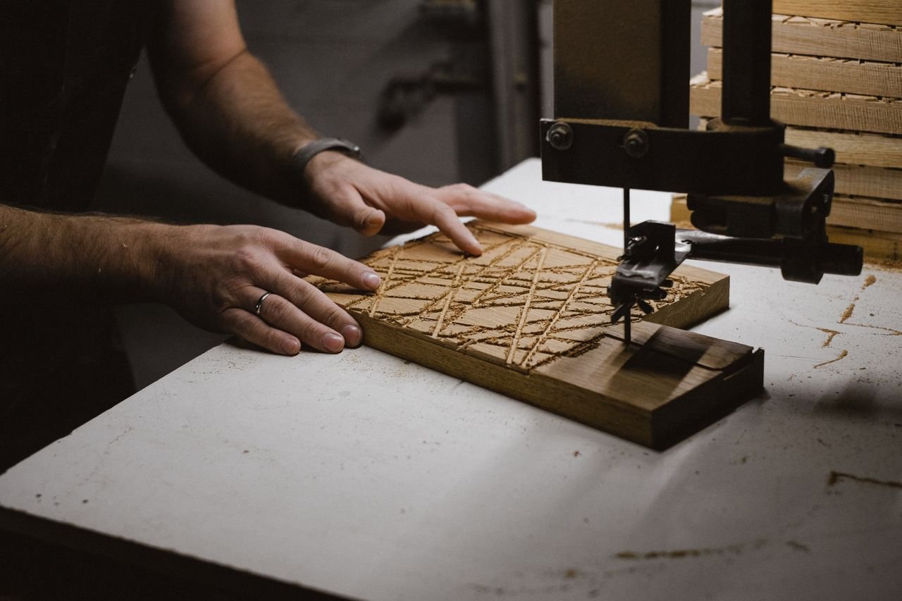 Crafting Captivating Headlines: Your awesome post title goes here Unrecognizable male master using sharp bandsaw machine while creating pattern on wooden plank in dark professional carpentry with equipment